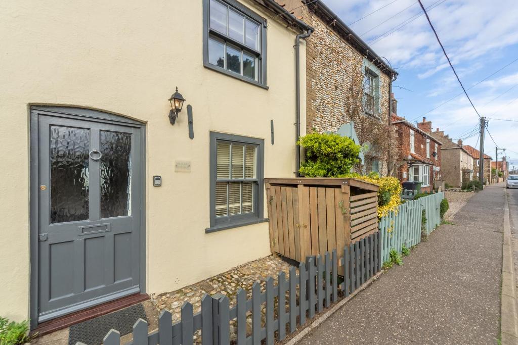 a house with a blue door and a fence at No33 BRACKEN BOUTIQUE COTTAGE in Brancaster