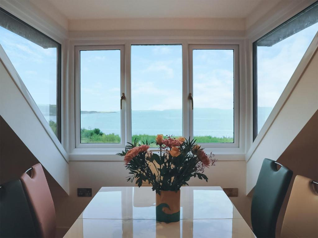 a vase of flowers on a table in front of windows at Headlands Hideaway in Coverack