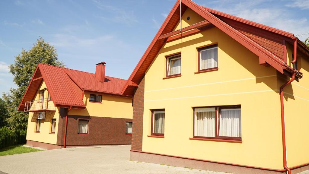 una casa amarilla con techo rojo en Suraučių Svečių Namai en Aukštadvaris