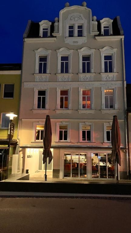 ein großes weißes Gebäude mit zwei Sonnenschirmen davor in der Unterkunft Maxplatz in Rehau