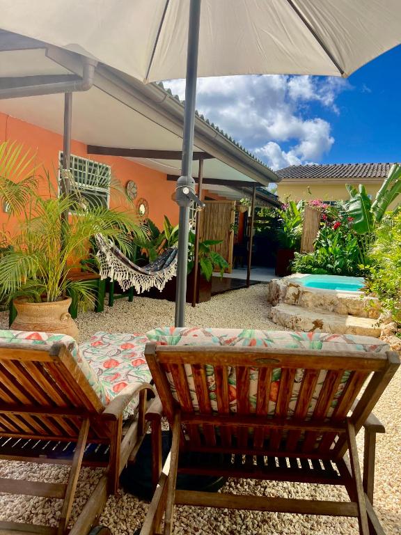 a patio with two chairs and an umbrella at Tropical Appartment & Studio Curaçao in Dorp Sint Michiel