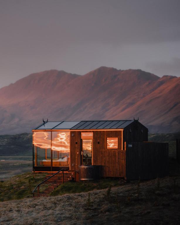 a house on a hill with mountains in the background at Panorama Glass Lodge SOUTH in Hella