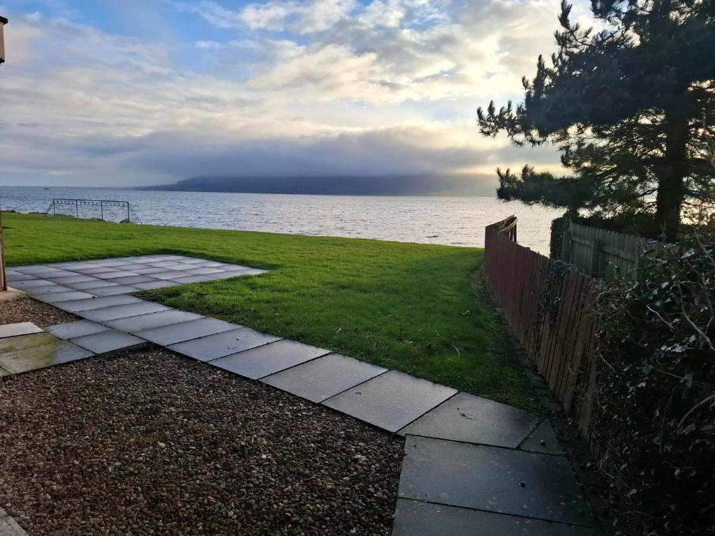 a walkway next to the water with a fence at Rostrevor Beach House in Rostrevor