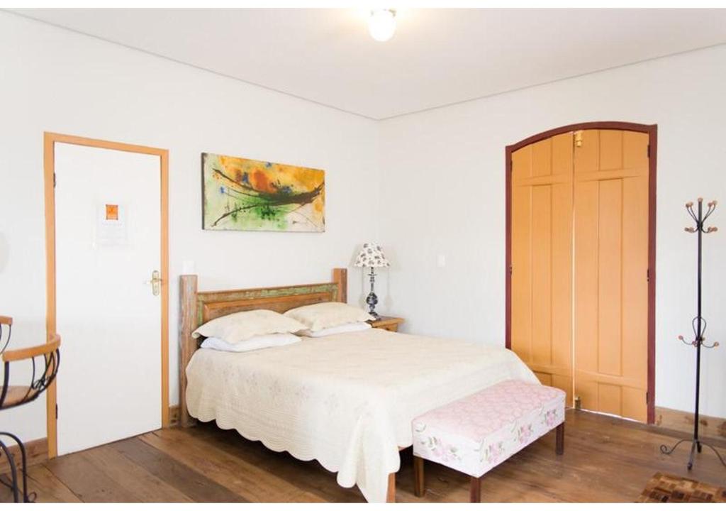a bedroom with a white bed and a wooden door at Lofts do Largo in Tiradentes