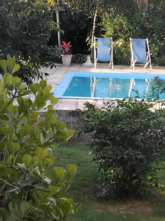 a swimming pool with two chairs in a yard at Espaço Bahia Bella in Porto Seguro
