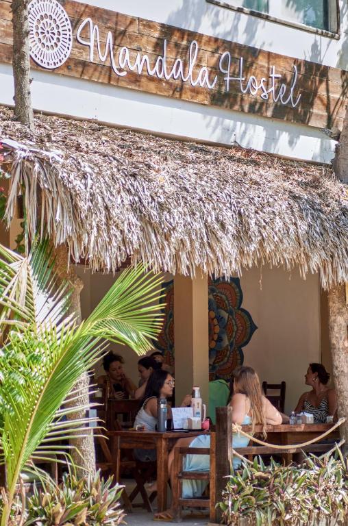 a group of people sitting at tables outside of a restaurant at Mandala Hostel Jeri in Jericoacoara