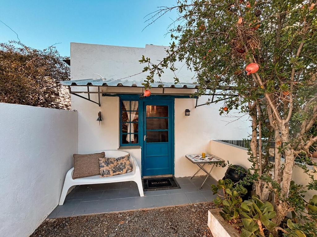 a porch with a blue door and a white chair at Buffelsrivier Farm Stay in Laingsburg