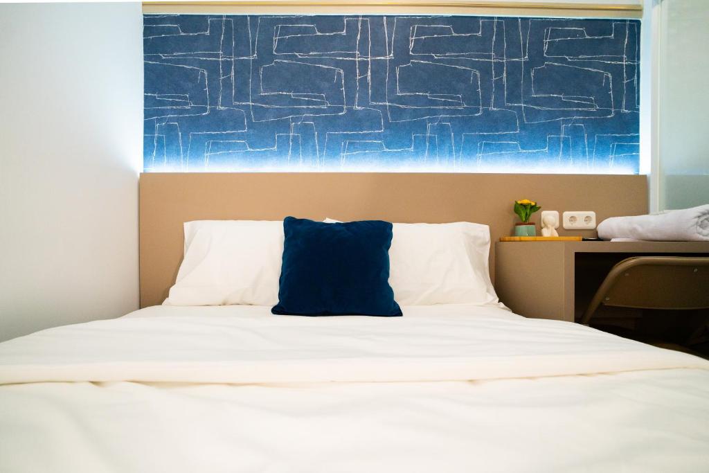 a bed with a blue pillow on top of it at Behomy Boarding Ciledug in Pasarjumahat-Kulon