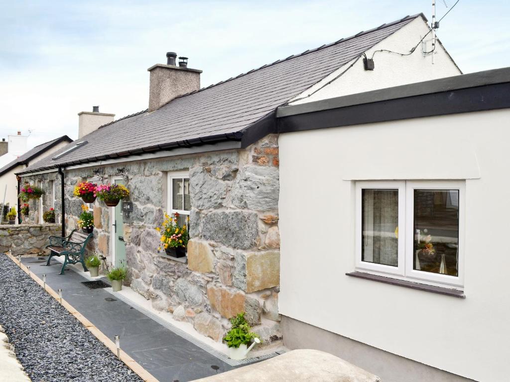 a stone cottage with flowers on the windows at Llifon in Llanwnda