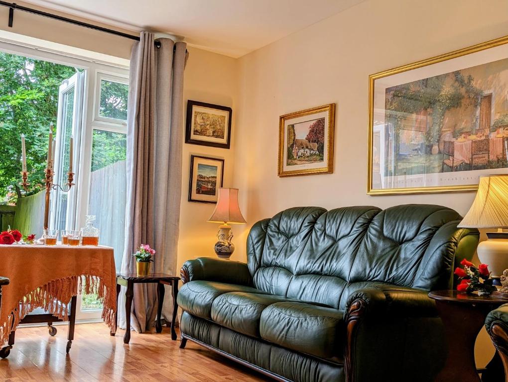 a living room with a leather couch and a table at Sherlock's Moray House -Idea long stay for contractors & family Two bedroom mid terrace 3 beds 2 sofa beds Sleep 5 Working facility Free WiFi TV & private parking Enclose rear garden dog friendly Sainsbury's & takeaway pubs in walking distance in Church Gresley