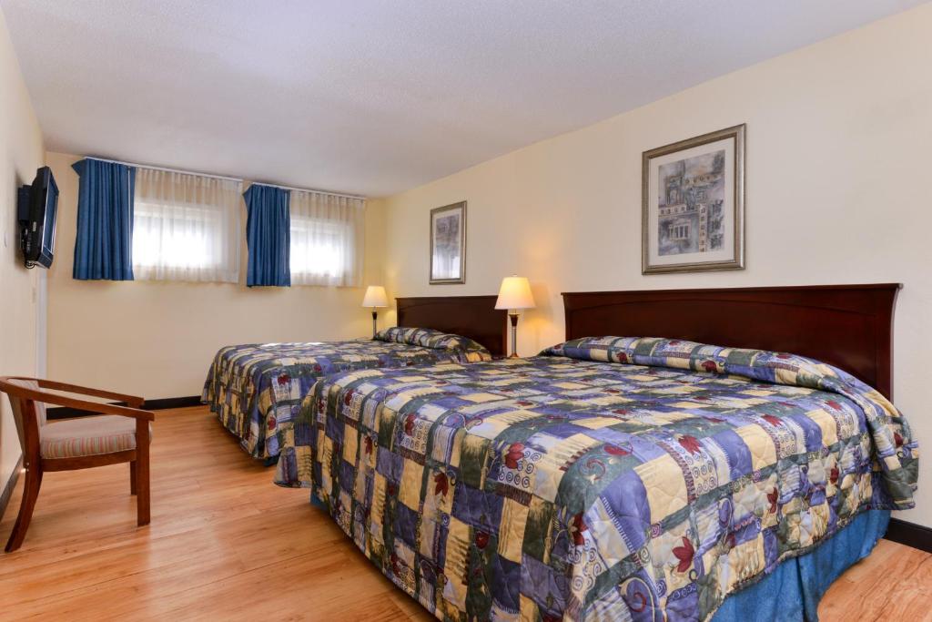 una habitación de hotel con 2 camas y una silla en Tower Inn and Suites of Guilford / Madison en Guilford