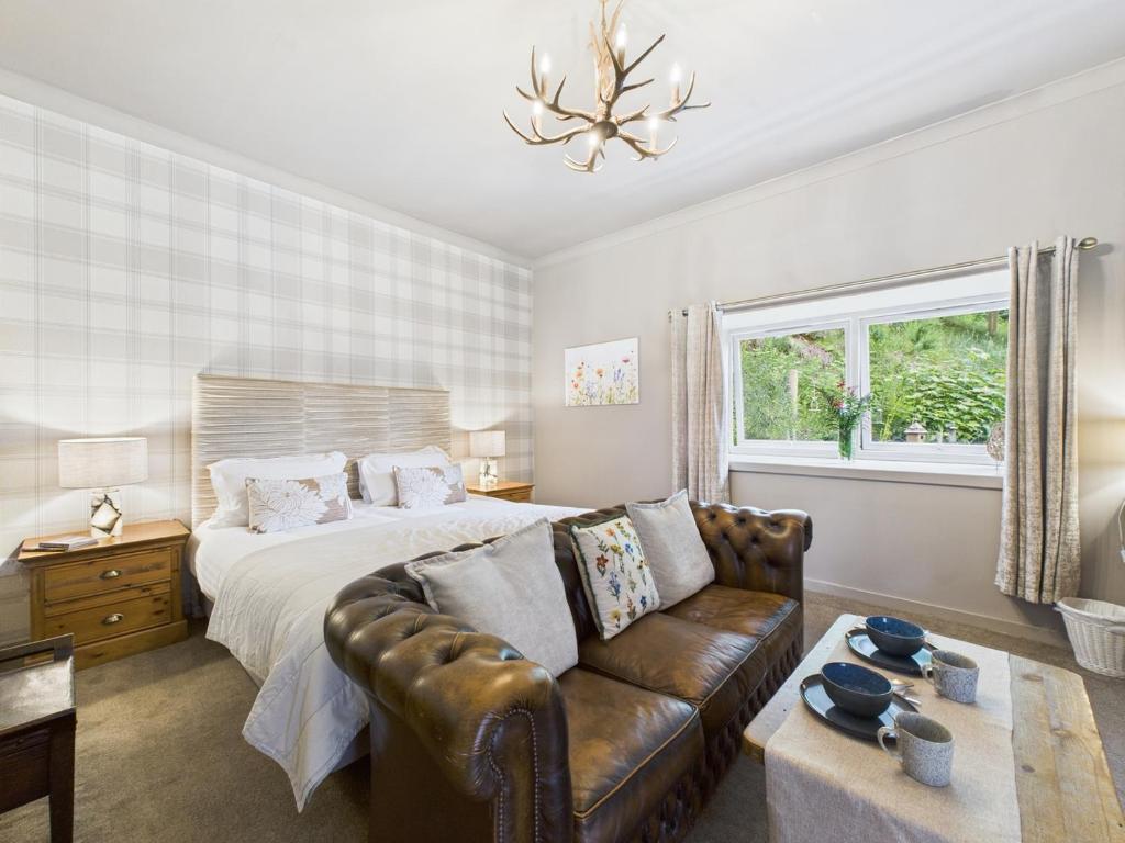 a bedroom with a bed and a leather couch at Glenshee Suite, Beechtree Cottage in Kirkmichael