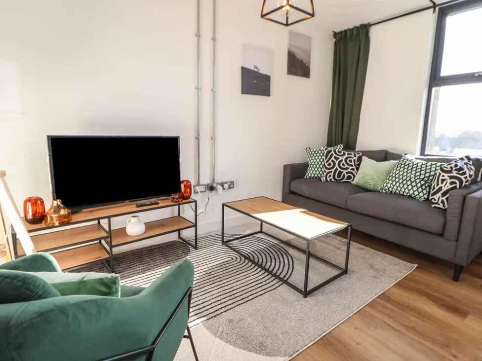 a living room with a couch and a flat screen tv at Woolston Central 2-Bedroom Apartment in Warrington