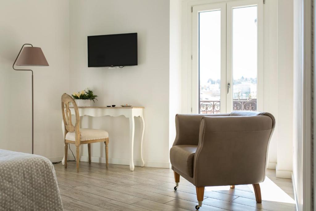 1 dormitorio con silla, mesa y TV en Residence Le Vie del Centro, en Matera