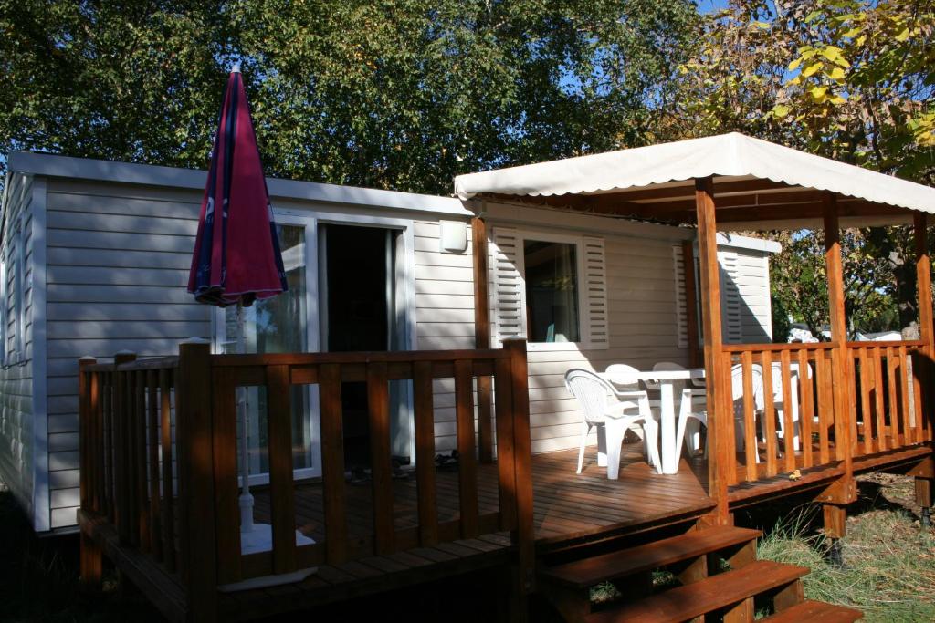 a deck with an umbrella and a table and chairs at Rêve en Famille in Gastes