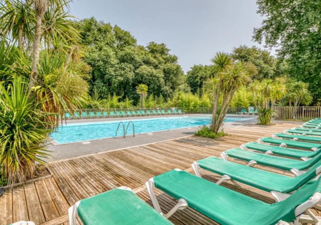 a group of lounge chairs next to a swimming pool at Camping La Clairière - Aquatique Vacances in Saint-Paul-en-Born