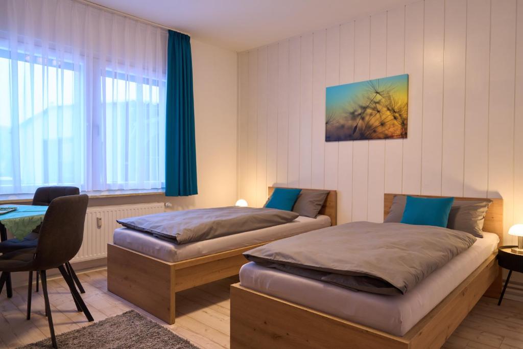 a bedroom with two beds and a table and a window at Gästewohnung Schöningen in Schöningen