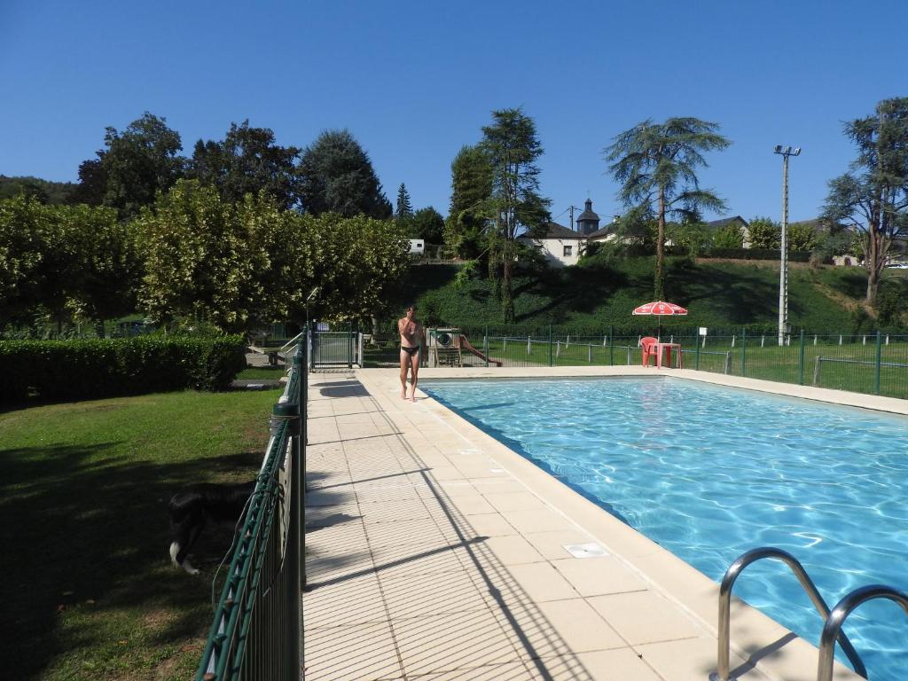 a person standing next to a swimming pool at CAMPING LE SAILLET Lestelle Betharram in Lestelle-Bétharram