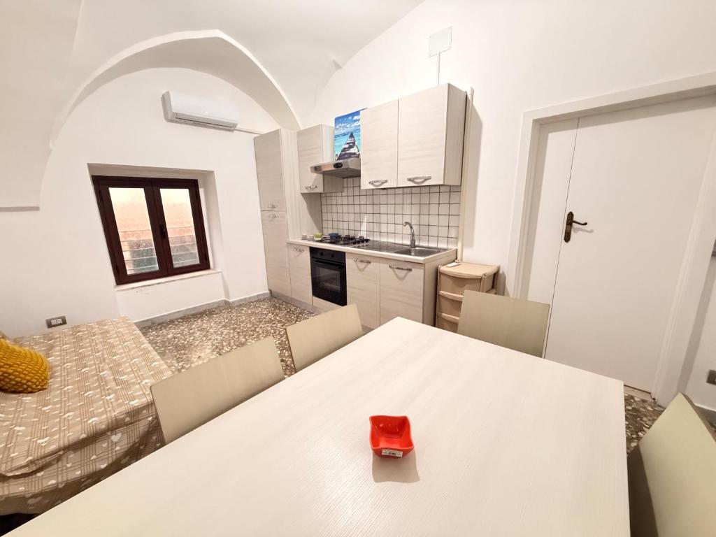 a kitchen with a white table with a red object on it at Scorcio Sul Mare in Gallipoli