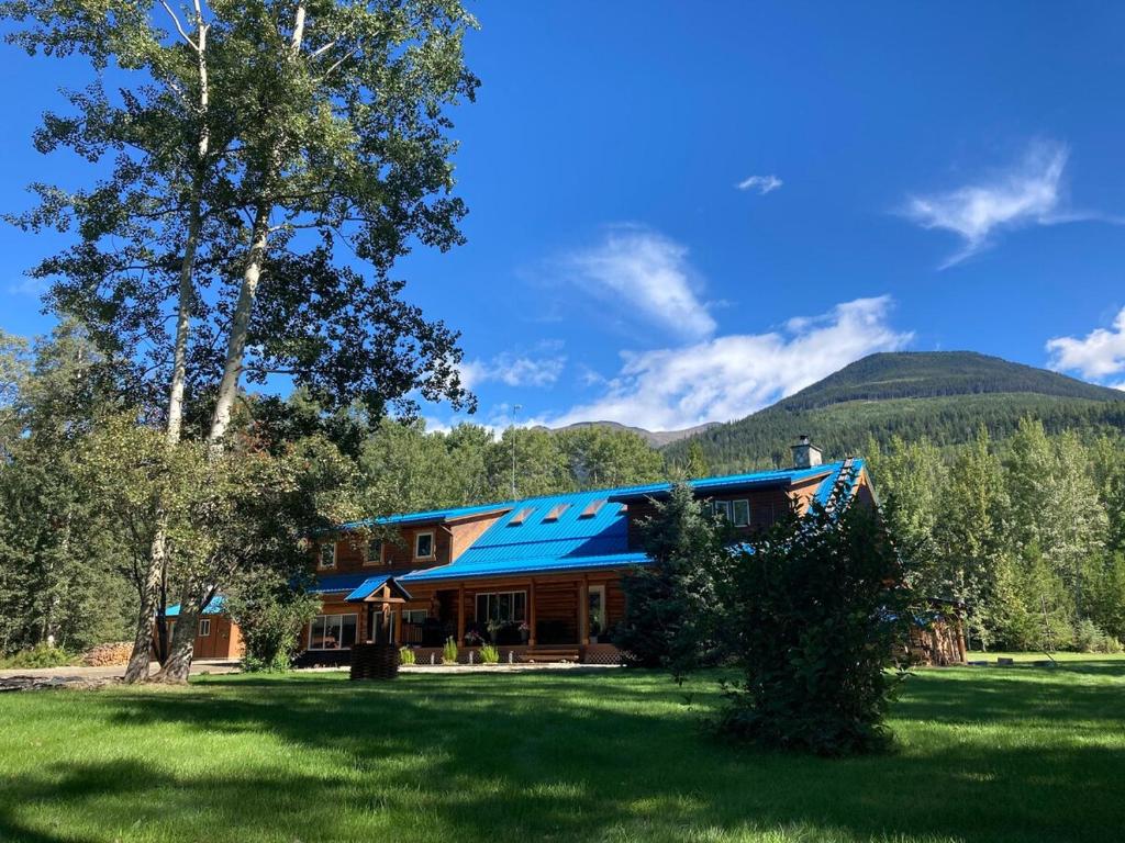 a house with a blue roof in a field at Cougar Mountain Lodge and Resort Cabin Rentals in Valemount
