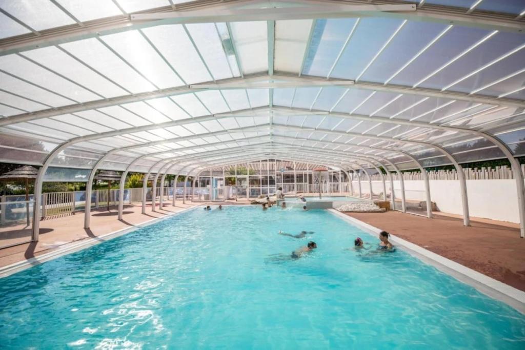 a swimming pool with people in the water at ZEcamping 3 animaux acceptés club enfant piscine couverte in Prigny