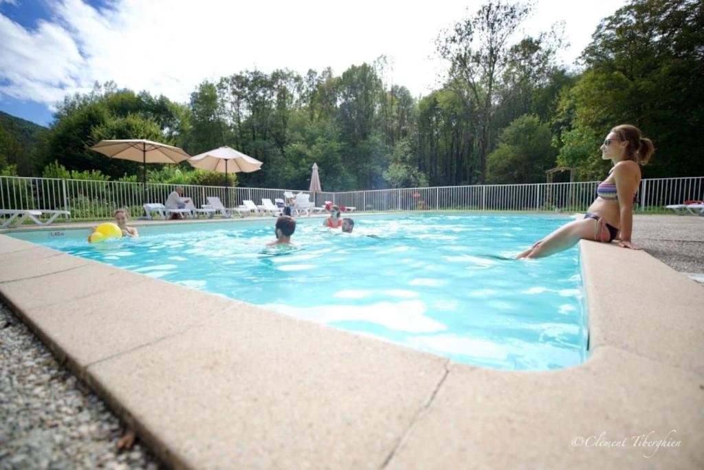 a woman sitting on the edge of a swimming pool at ZEcamping 4 pet friendly club enfant piscine bar et restanrant in La Bastide-de-Sérou