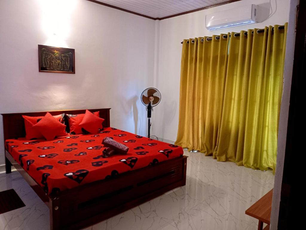 a bedroom with a bed with red sheets and yellow curtains at Villa Keturah in Katunayaka