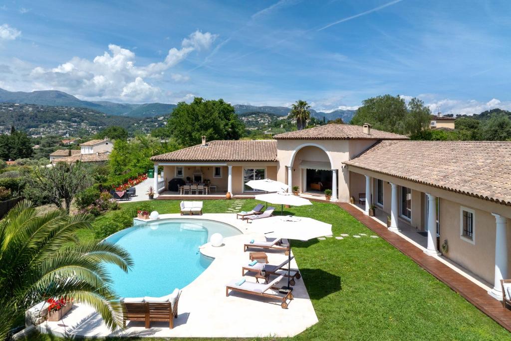 a pool with chairs and umbrellas next to a house at Villa Sole Flats in Saint Paul de Vence