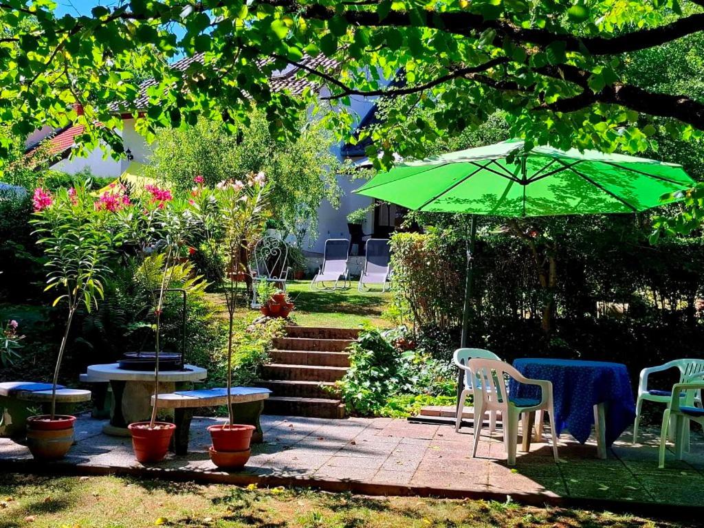 a patio with a green umbrella and tables and chairs at Villa Vadása Vendégház in Hegyhátszentjakab