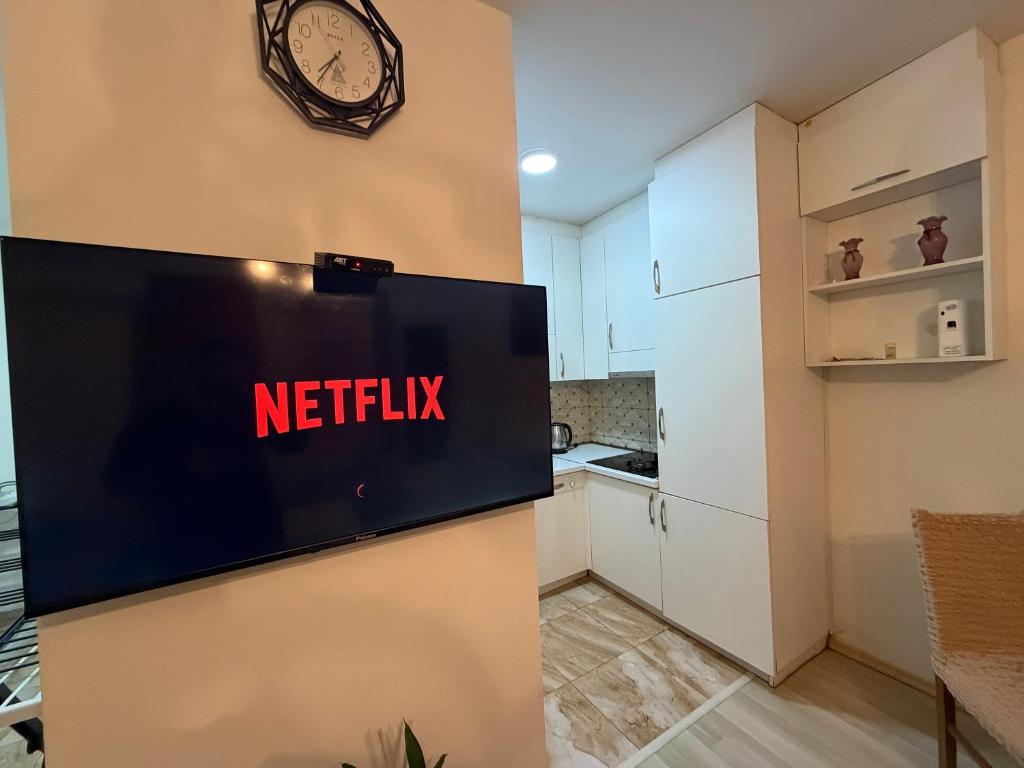 a kitchen with a tv and a clock on a wall at Cozy Apartment in Prishtinë