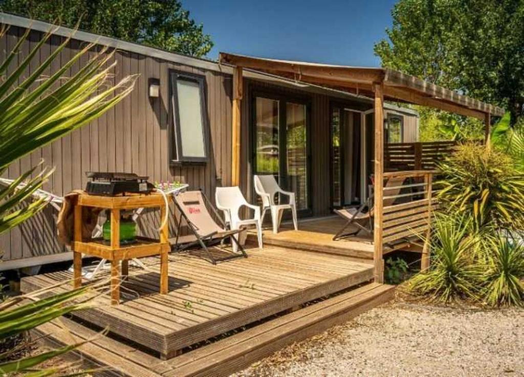 a cabin with a wooden deck with a table and chairs at Camping 4 etoiles - Espace aquatique - 500m plage - ccagefg in Portiragnes