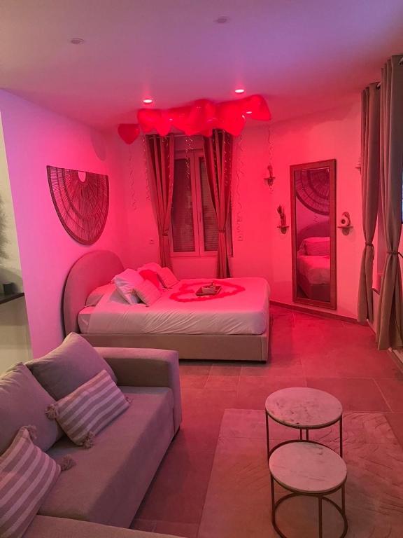 a pink room with two beds and a couch at Jardin eden88 in Saint Die