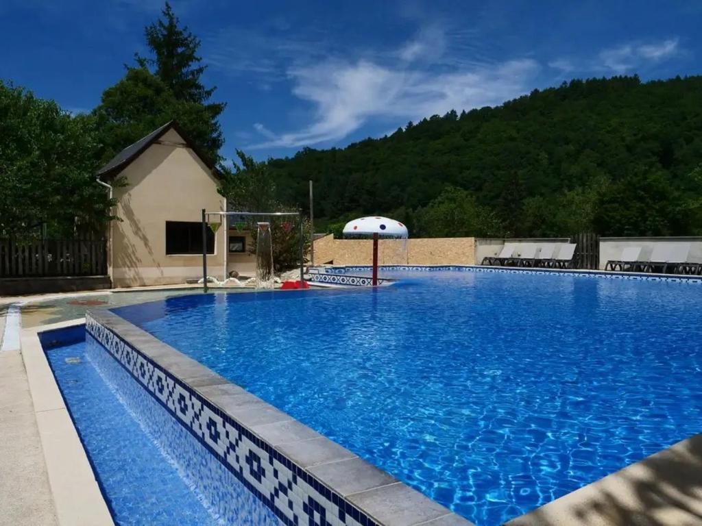 a large blue swimming pool with an umbrella at Chalet 4 étoiles - Piscine - ef0c00 in Monceaux-sur-Dordogne