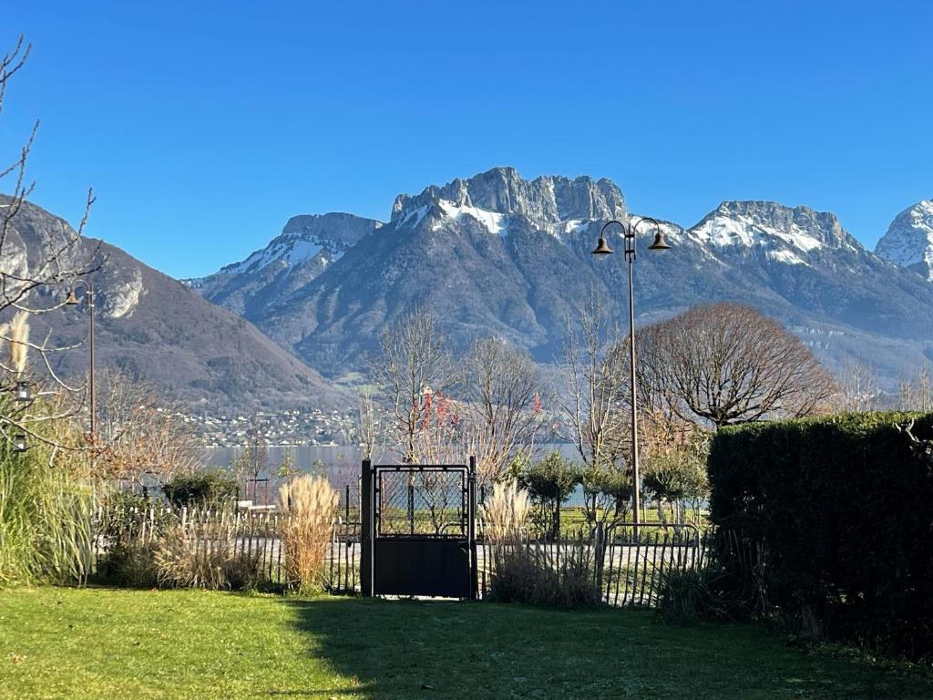 a gate in a park with mountains in the background at Le Chalet de la Plage in Sévrier