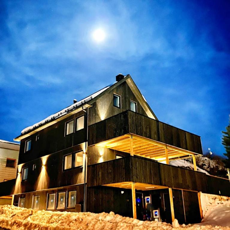 a wooden house with the moon in the background at Sentral toppleilighet 3.etg 4 pers in Svolvær