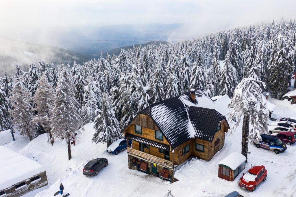 a house in the snow with cars parked in front of it at Cabana Vitus Panzió in Harghita-Băi