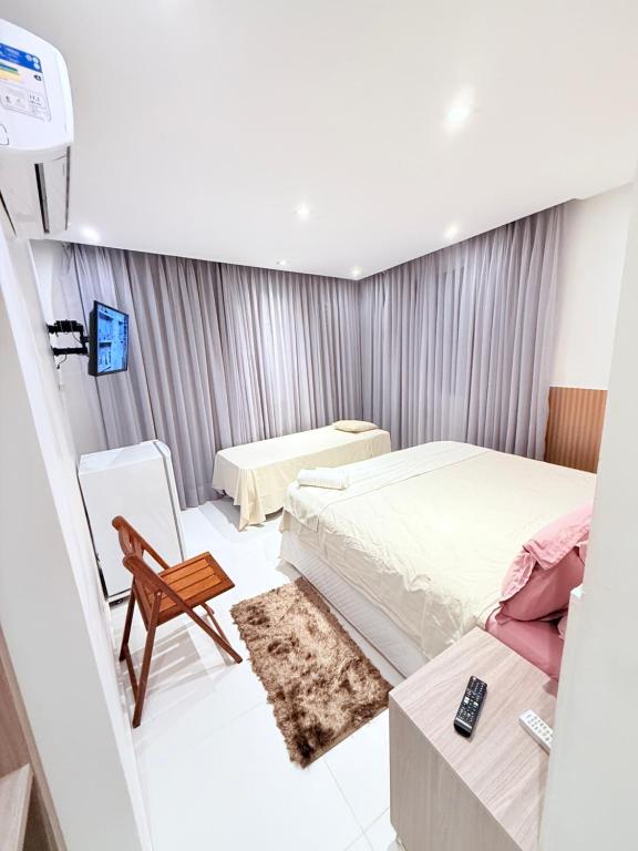 a small bedroom with two beds and a chair at Vila do Morro Pousada in Morro de São Paulo