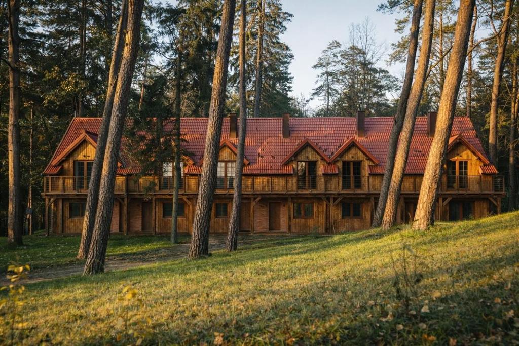 a house with a red roof in the woods at Leśna Przystań apartamenty dwupoziomowe nad jeziorem in Węgorzewo