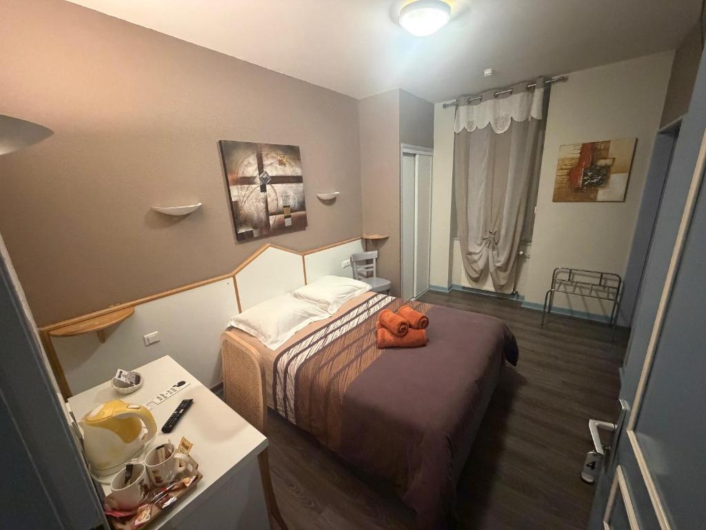 a small hotel room with a bed and a table at Hôtel du Centre in Gueugnon