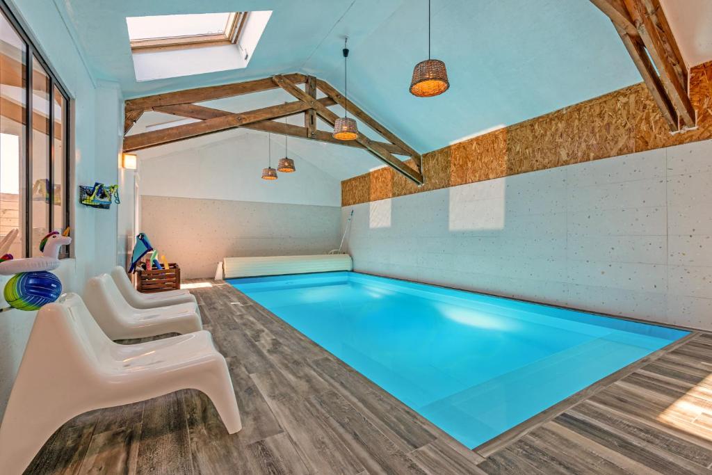 a swimming pool in a room with two white chairs at Weekend dans la villa Léonie in Kerlouan