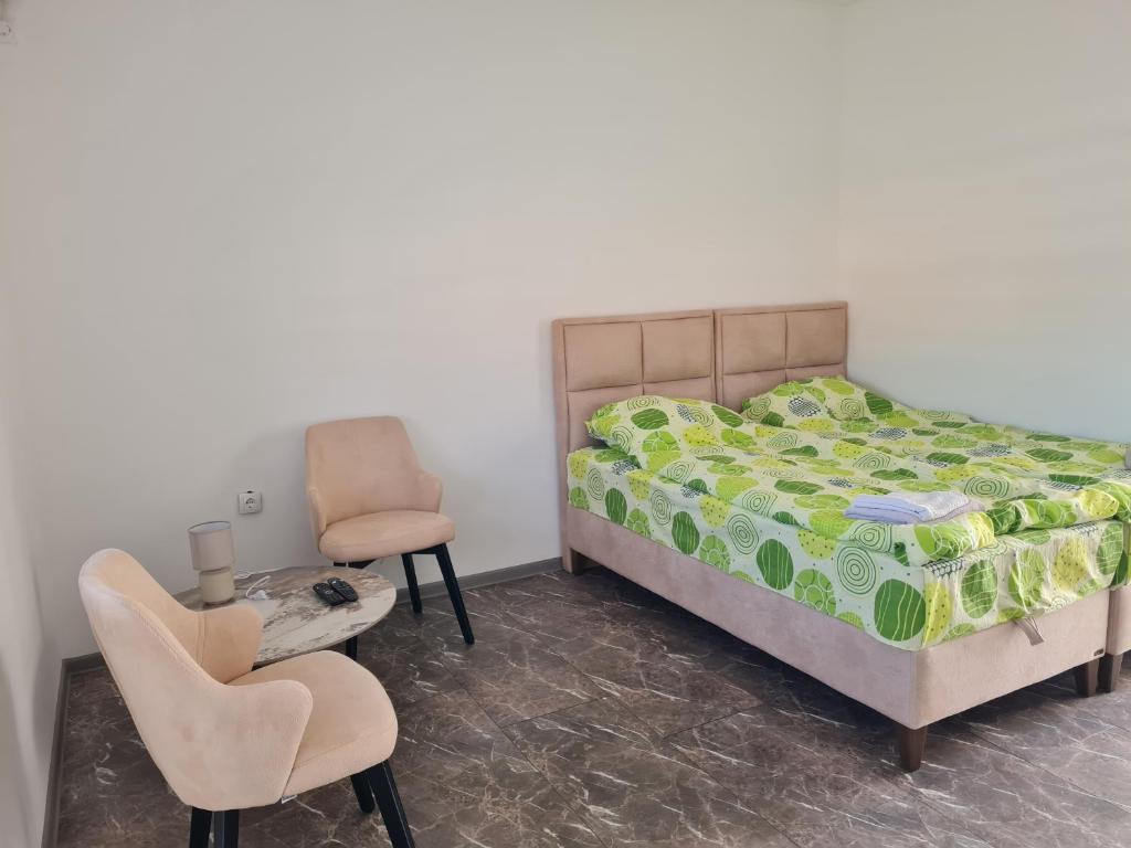 a bedroom with a bed and two chairs and a table at Smeštaj kod Lazarice Šid in Šid
