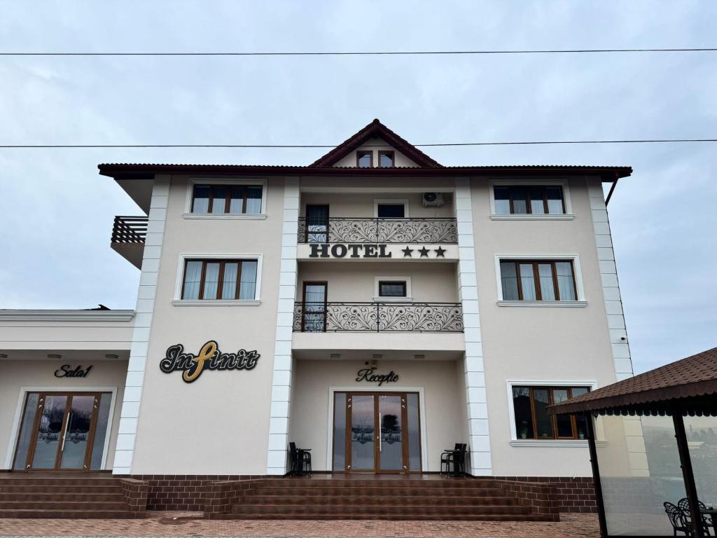 a large white building with a balcony at Hotel Infinit in Târgu Jiu