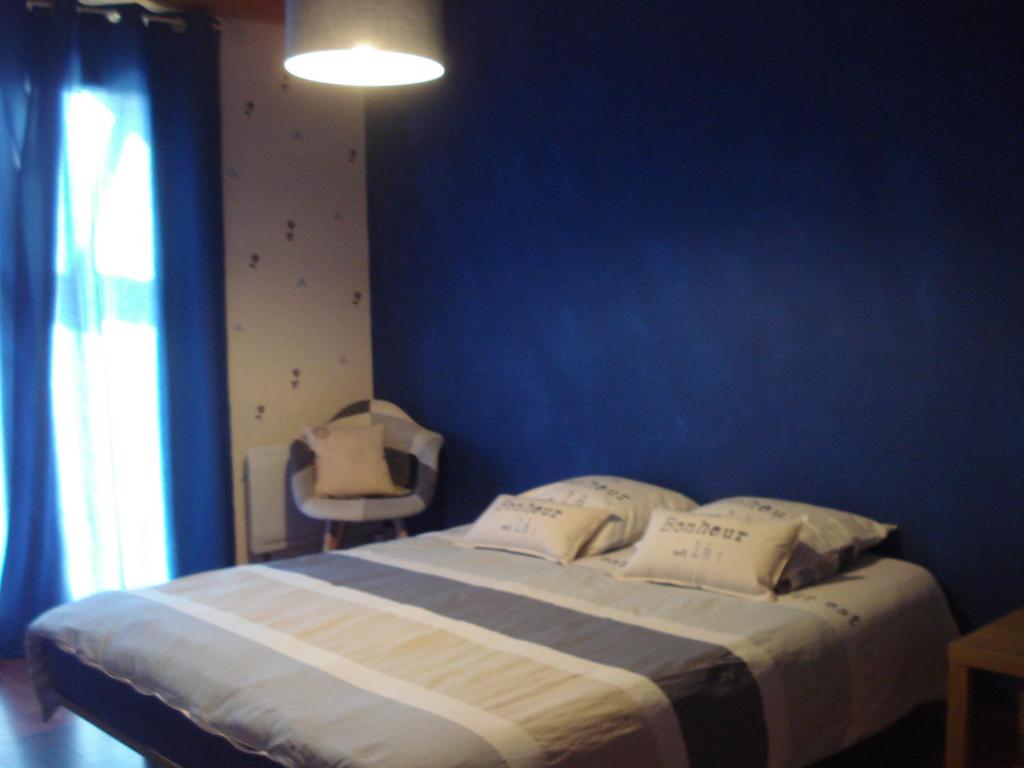 a bedroom with a large bed with a blue wall at Domaine des cigales, chambre d'hôtes in Saint-Martin-dʼAoût