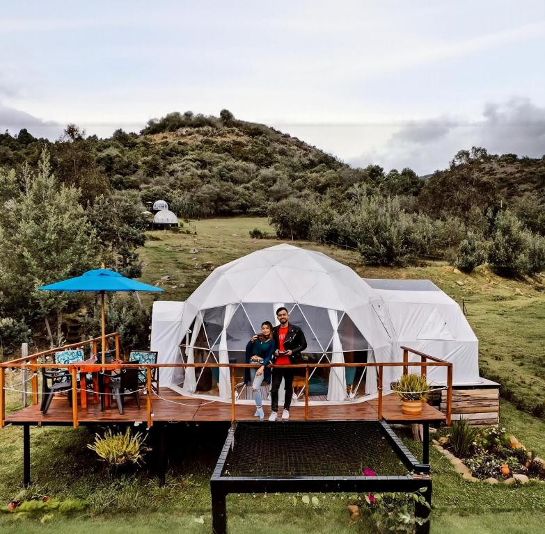 two people standing in front of a tent at Glamping Claro de Luna in Guatavita