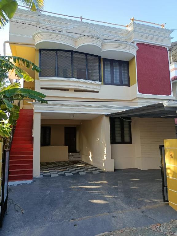 a yellow and white house with a red staircase at Dwaraka Serviced Villa - Near Sree Padmanabha Swamy Temple, Trivandrum -AC Rooms & Parking in Trivandrum