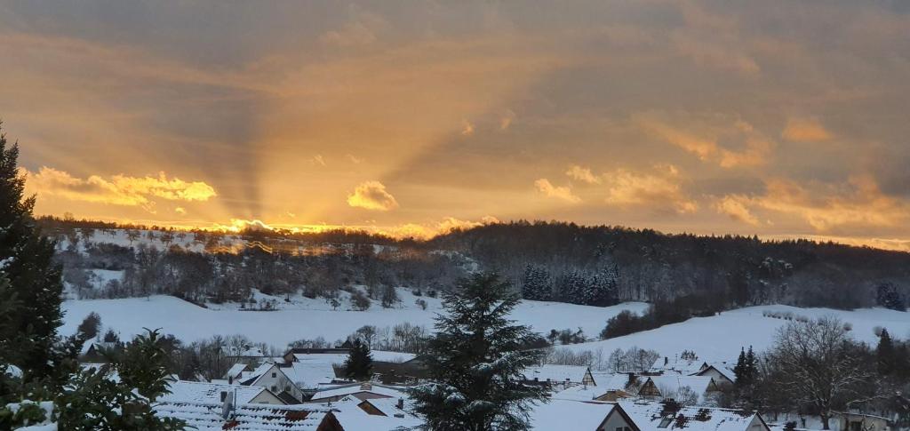 a snow covered village with a rainbow in the sky at Ferienwohnung Vogelsang in Sachsenheim