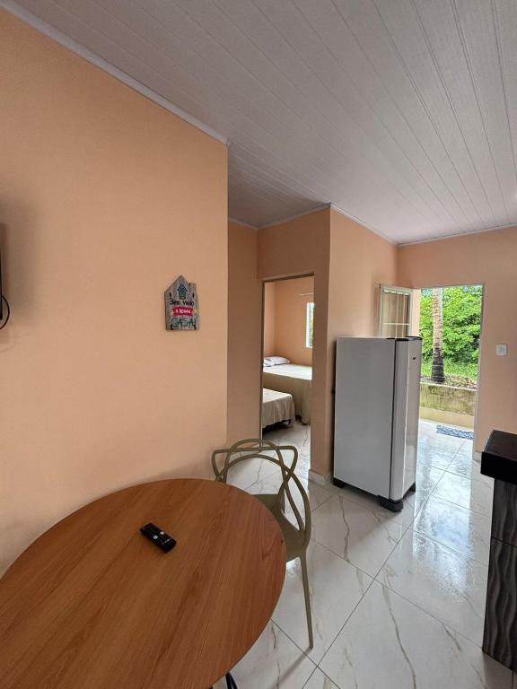 a kitchen with a wooden table and a refrigerator at pousada Bela Rosa in Santa Cruz Cabrália