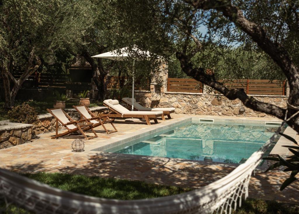 a swimming pool with two chairs and an umbrella at Joya Luxury Villas in Kypseli
