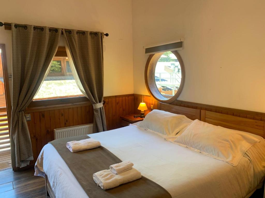 a bedroom with a bed with two towels on it at HOTEL & HOSTAL CHIL'IN, Las Trancas in Las Trancas