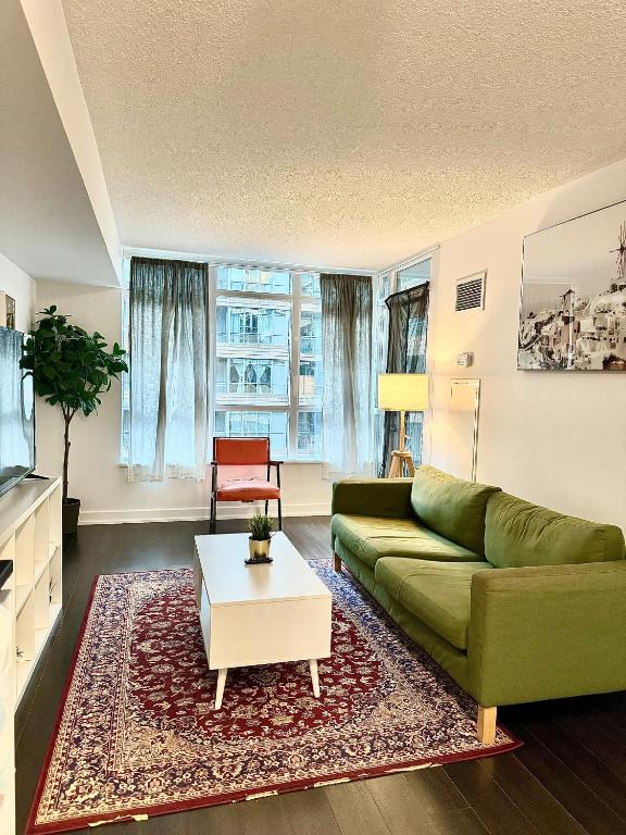 a living room with a green couch and a coffee table at Cozy Condo near CN Tower in Toronto
